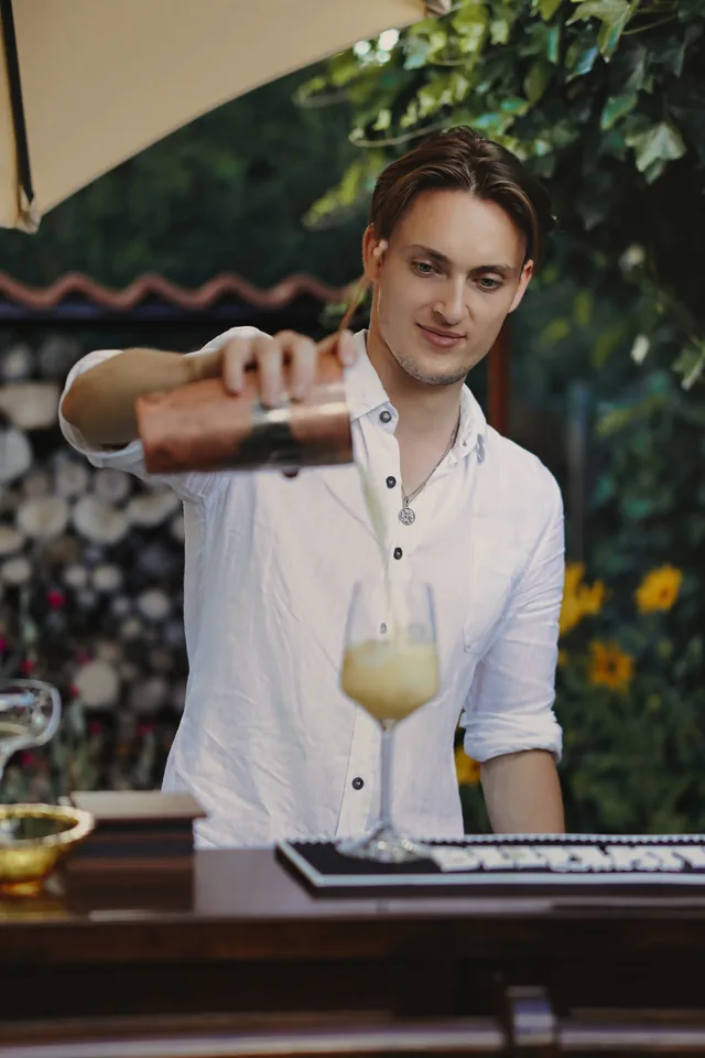 Ein Barkeeper schenkt einen Drink durch ein Barsieb ein.
